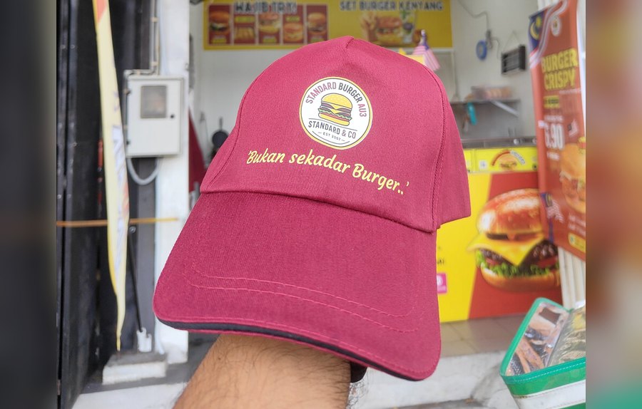 Standard Burger cap held in front of the Keramat AU3 shop